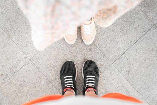 Two pairs of stylish sneakers on city pavement, perfect for fashion and lifestyle themes.