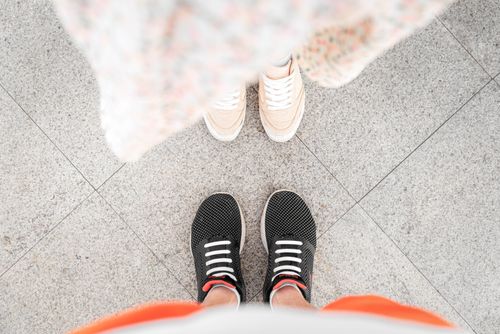 Free Two pairs of stylish sneakers on city pavement, perfect for fashion and lifestyle themes. Stock Photo