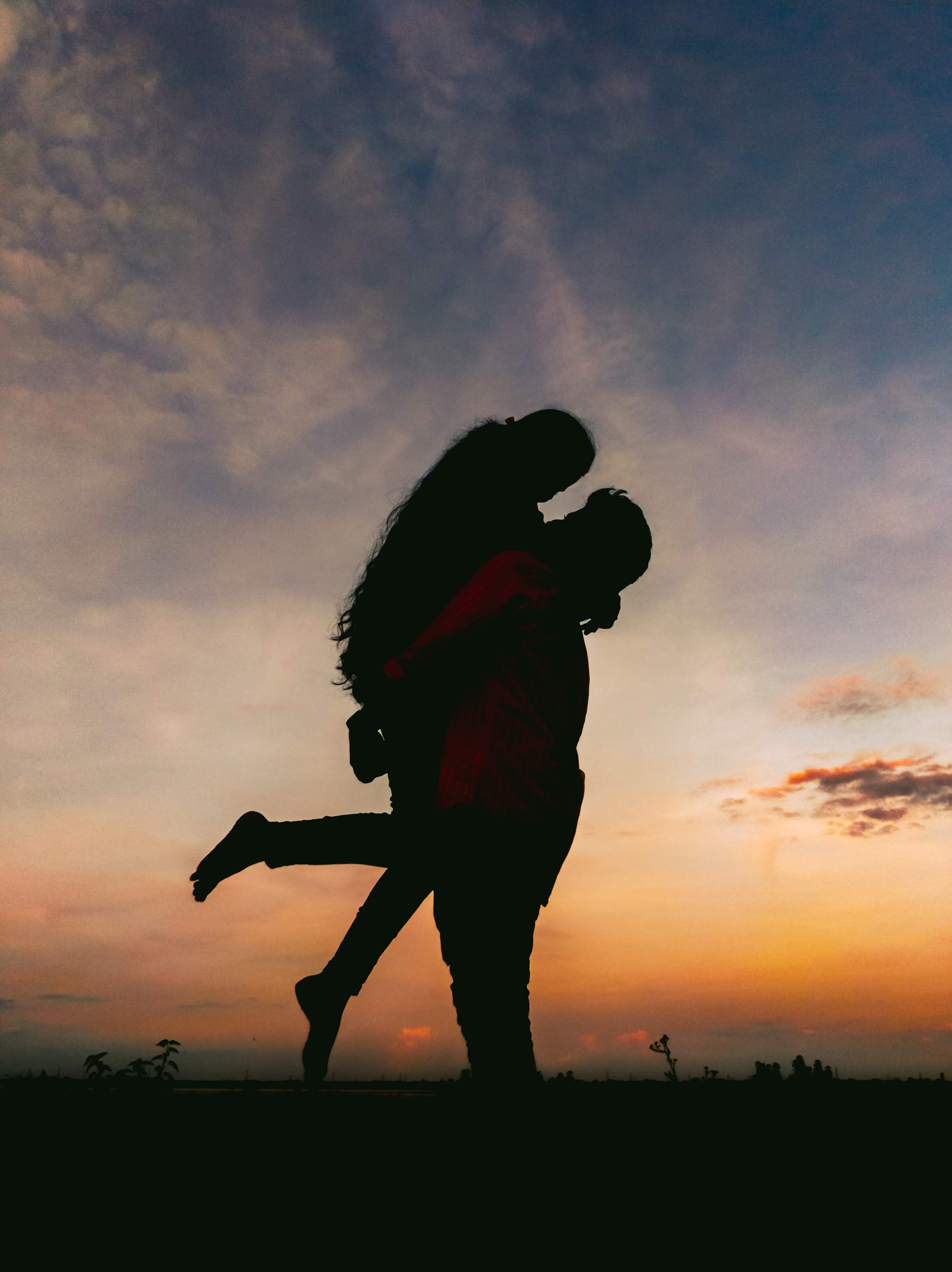 A couple's silhouette against a vibrant sunset at Sri Ram Sagar Project, Telangana.