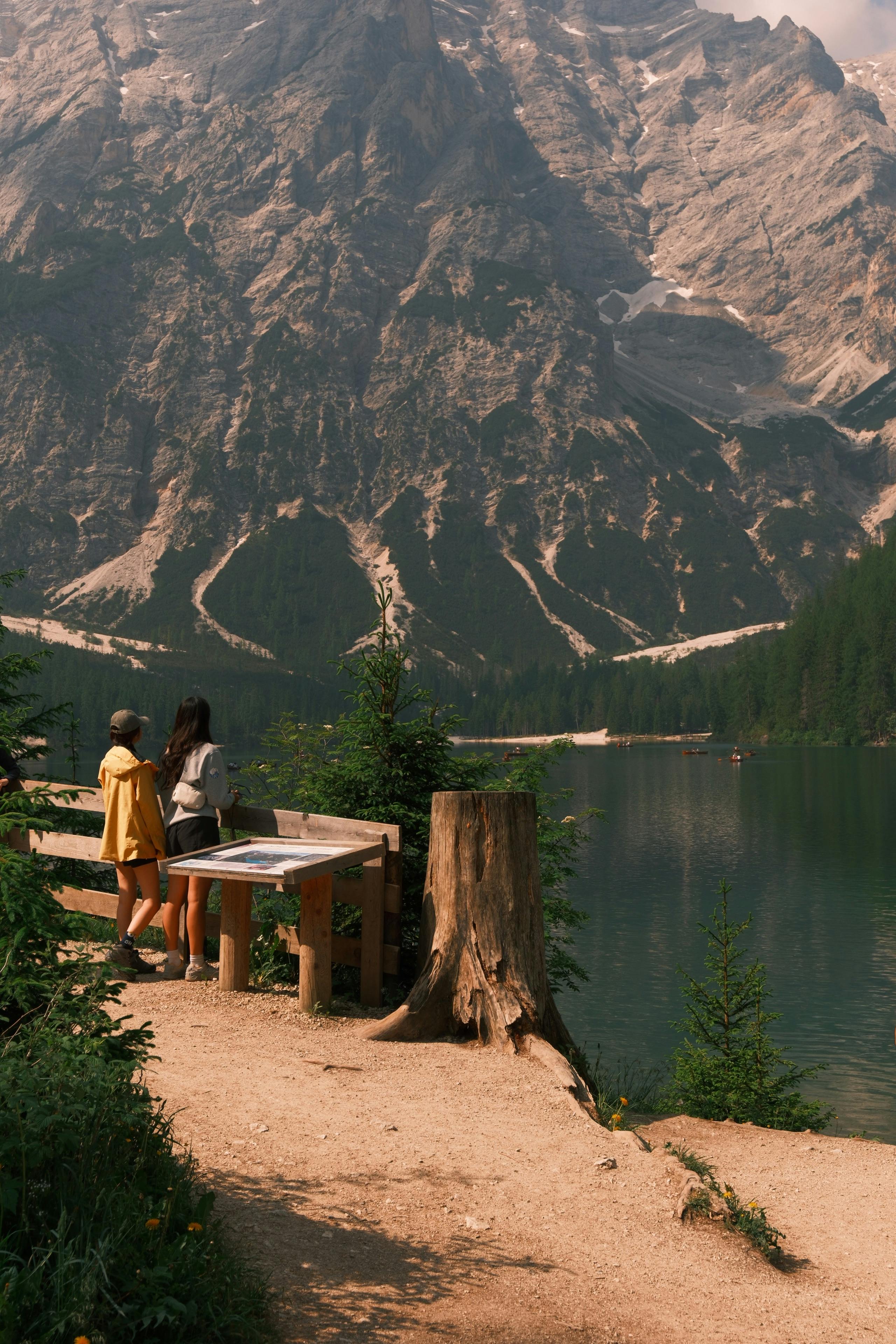Two people admire the stunning landscape of Lake Braies and Dolomites mountains in Trentino, Italy.