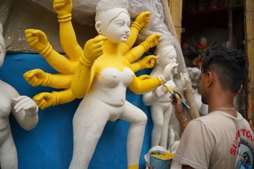Free Craftsman skillfully paints a Durga idol, highlighting the vibrant creativity and cultural artistry. Stock Photo