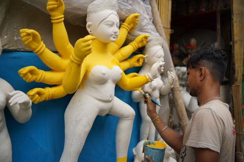 Free Artist meticulously paints a Durga idol, showcasing traditional craftsmanship and cultural celebration. Stock Photo