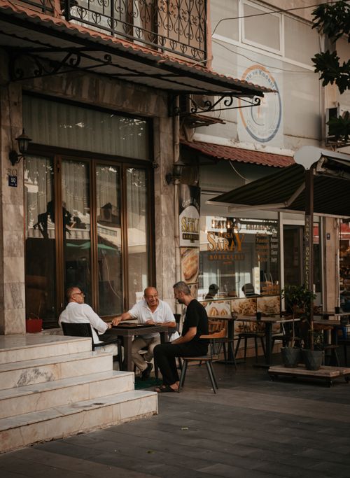 Free Group of men enjoying conversation at an outdoor cafe in a city setting. Stock Photo