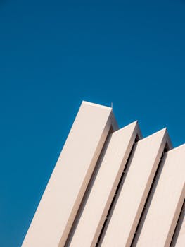 Striking geometric architecture with clean lines against a clear blue sky. Modern and minimalist style.