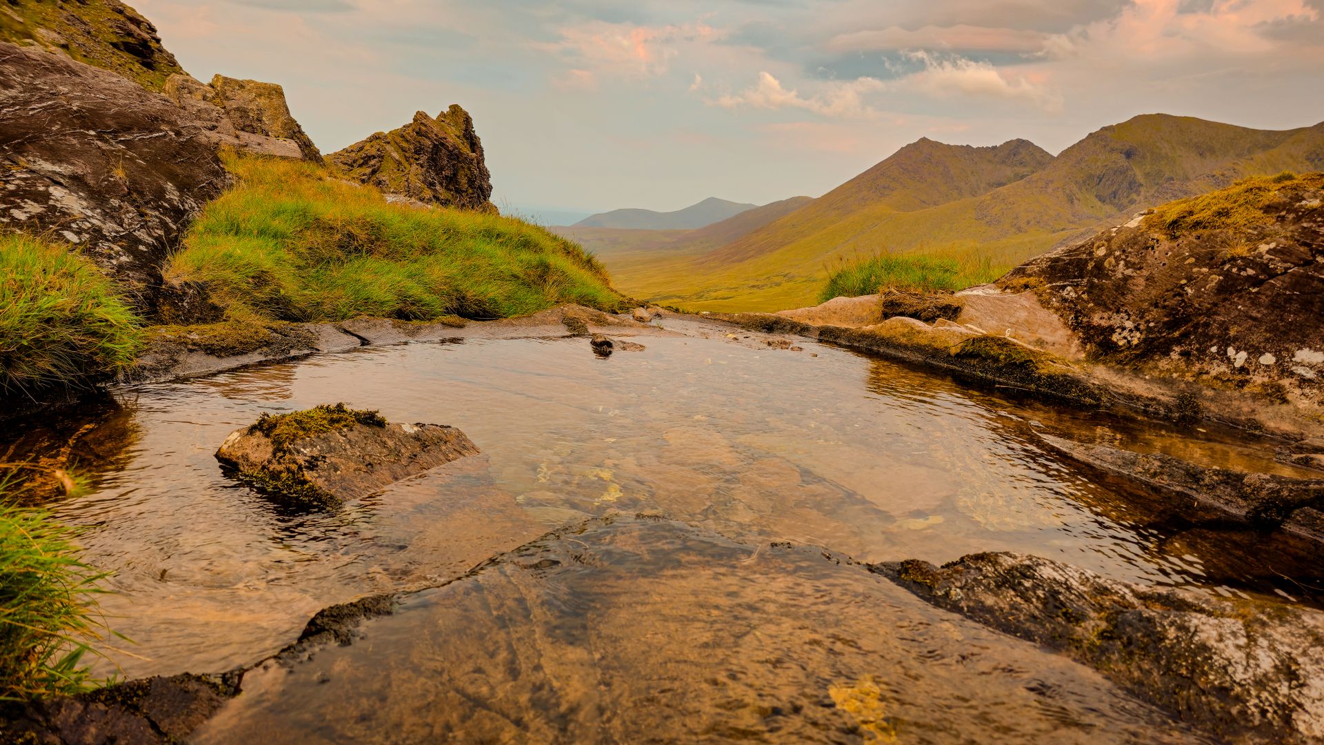A serene mountain stream in Ireland's Kerry offers breathtaking views of lush landscapes and rocky formations.
