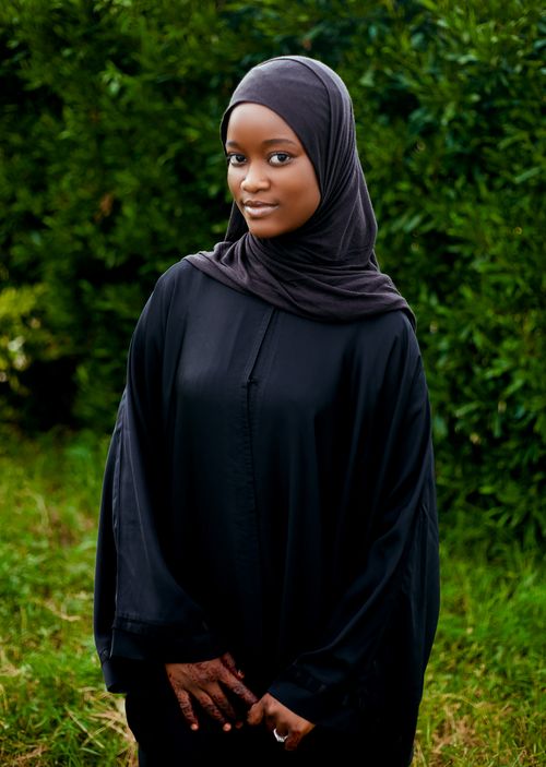Free Beautiful portrait of a young woman wearing a black hijab standing in a garden. Stock Photo