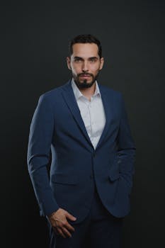 Confident man in a blue suit posing against a dark background.