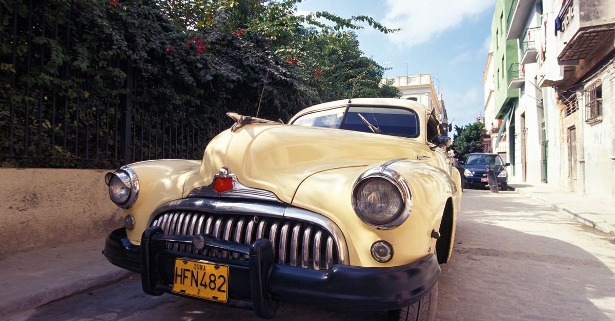 A classic yellow car parked on a sunny street in Havana, Cuba featuring vibrant colors and retro charm.