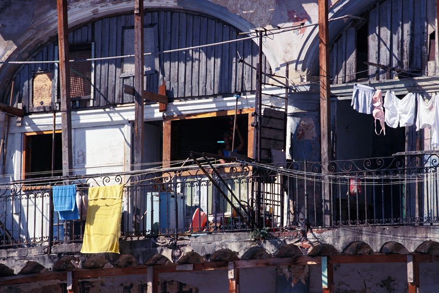 Rundown Cuban balcony with colorful laundry drying in the sunlight.