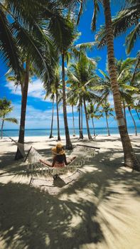 Relax on a hammock under palm trees by the clear waters in Central Visayas, Philippines.