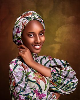 Captivating portrait of a smiling woman in traditional Nigerian attire against a warm backdrop.