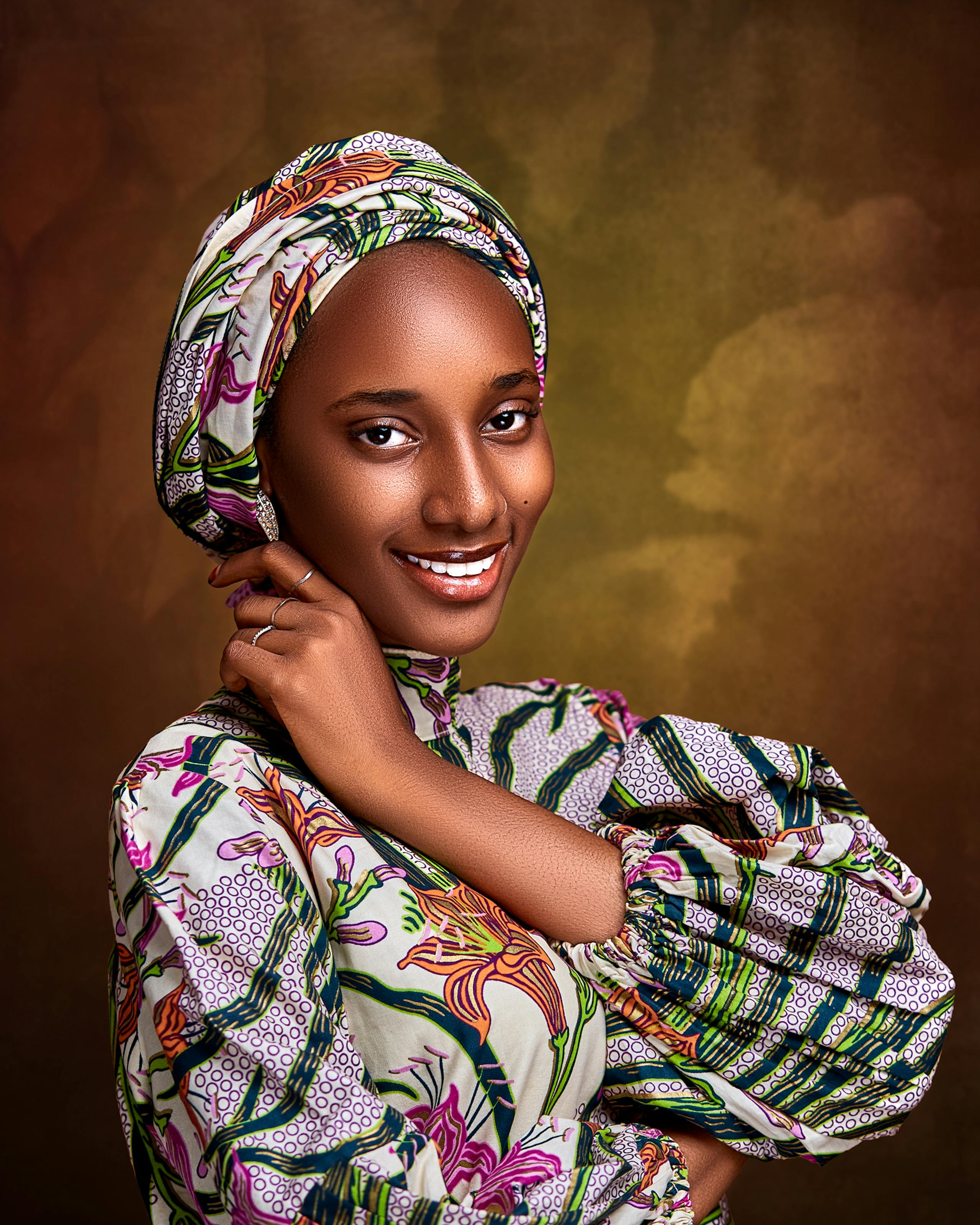 Free Captivating portrait of a smiling woman in traditional Nigerian attire against a warm backdrop. Stock Photo