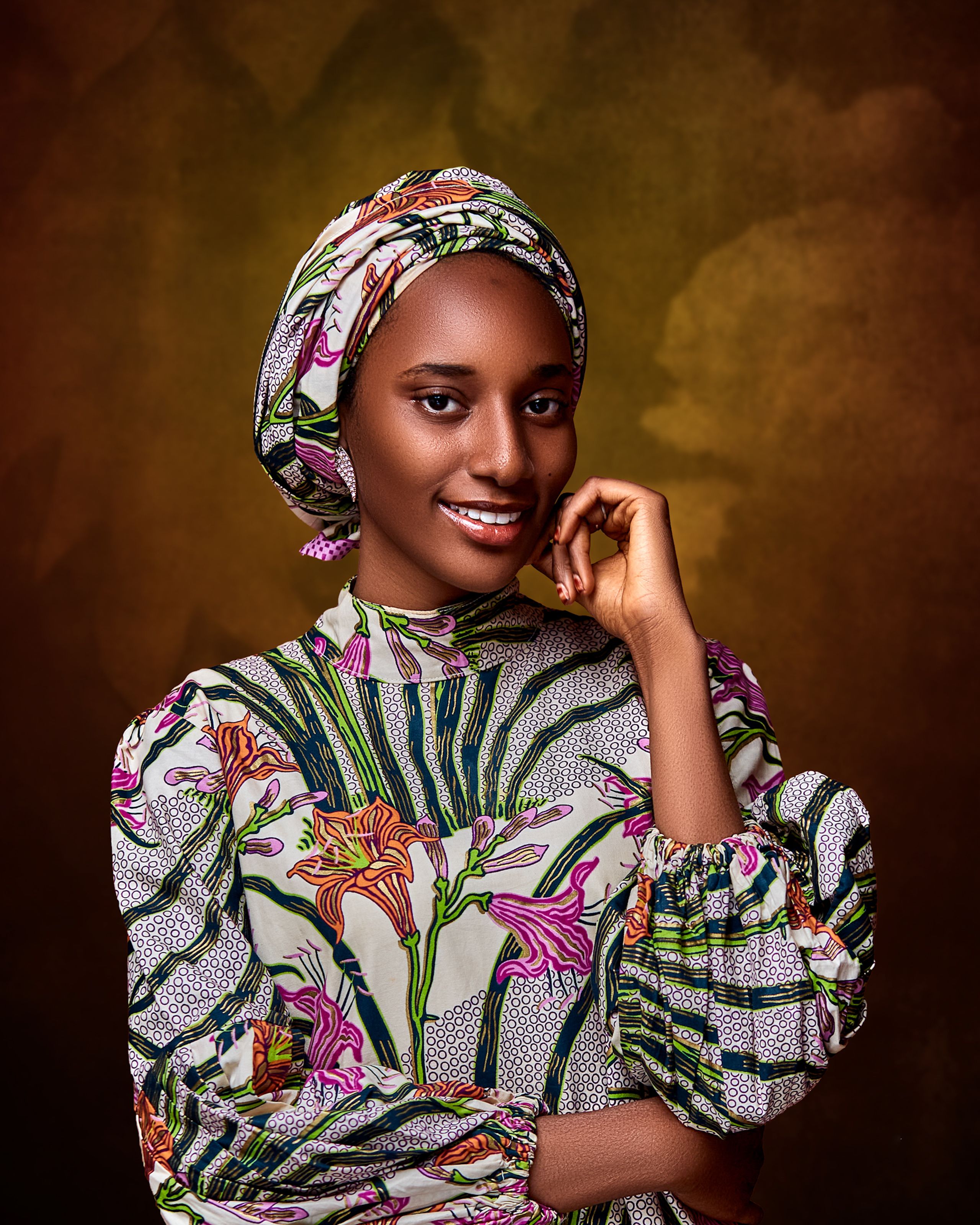 Beautiful portrait of a smiling Nigerian woman in traditional attire against a textured background.