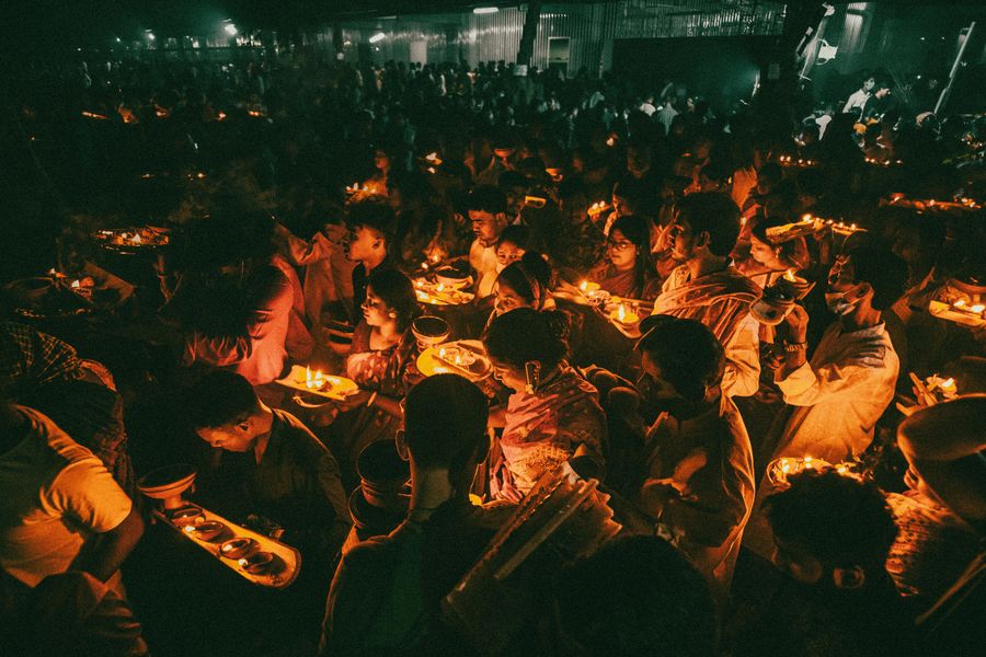 A festive crowd illuminated by candlelight during a vibrant celebration at night, creating a warm and communal atmosphere.
