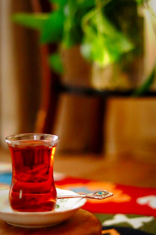 Free A warm setting featuring a glass of black tea on a saucer amidst indoor decor. Stock Photo
