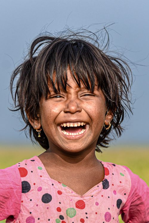 Free Cheerful young girl laughing against a clear blue sky in an outdoor setting. Stock Photo
