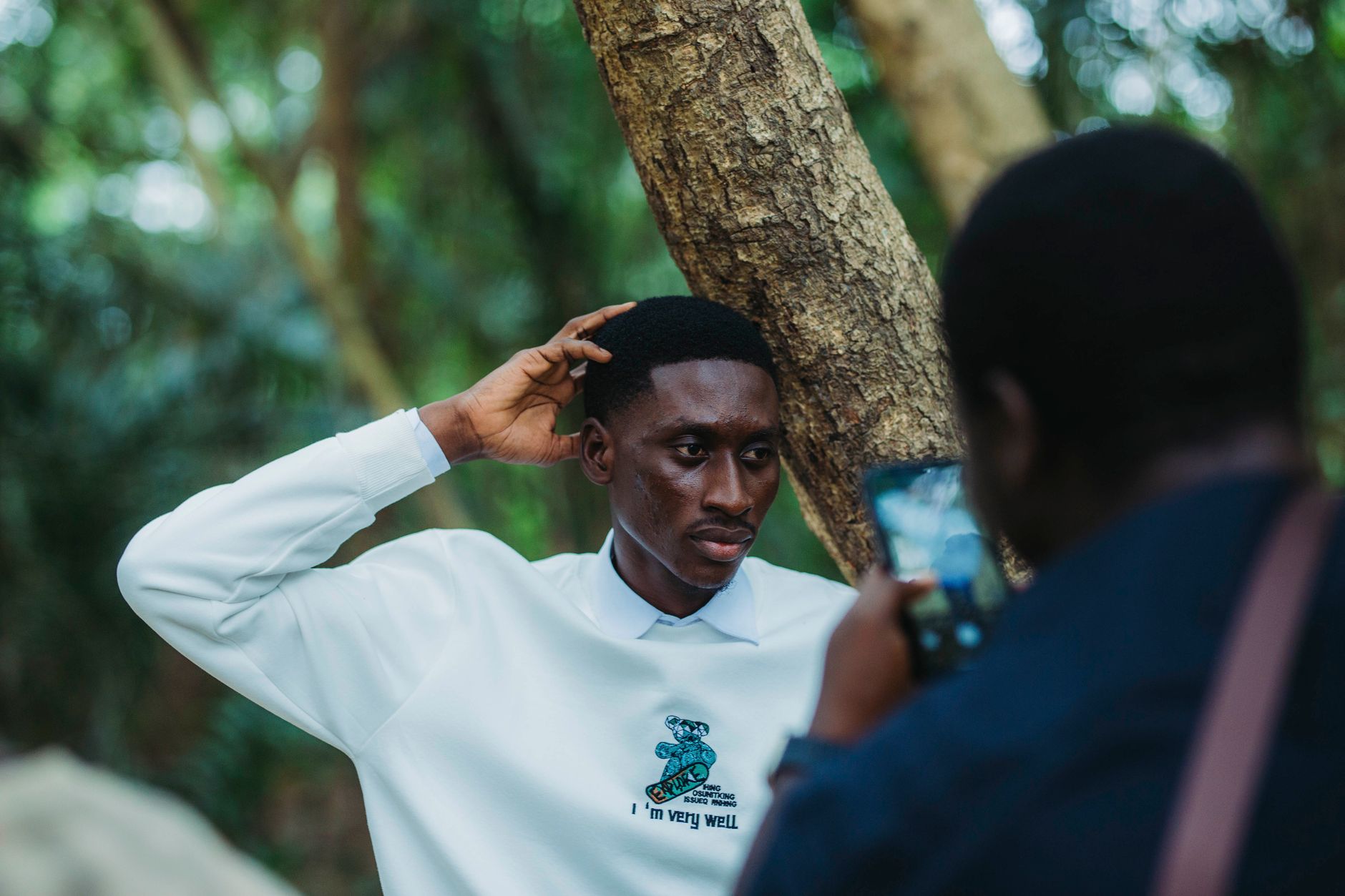 Man posing candidly in an outdoor portrait shoot in Accra's lush forest setting.
