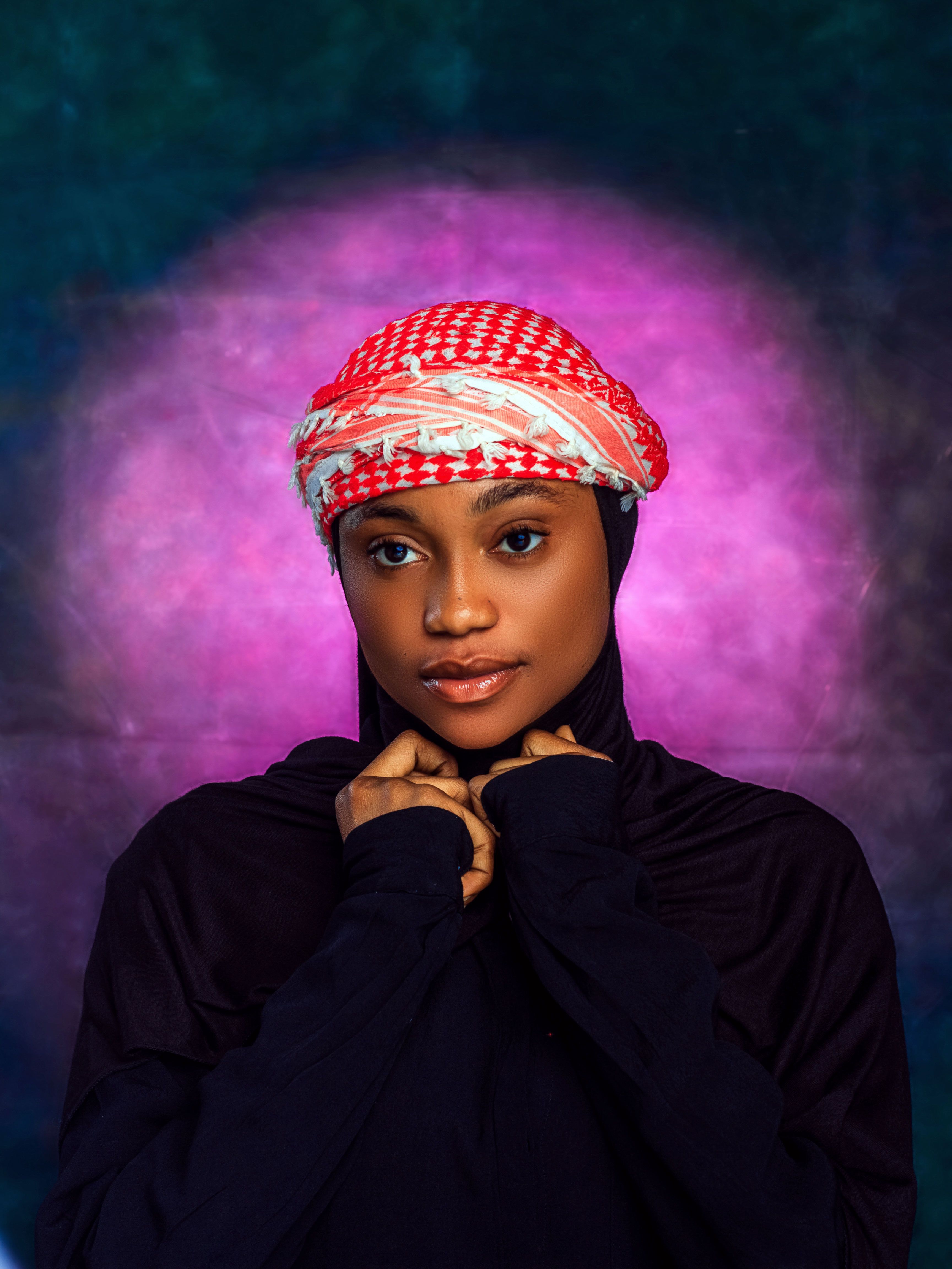 Striking portrait of a woman wearing a shemagh with vivid purple and blue background.