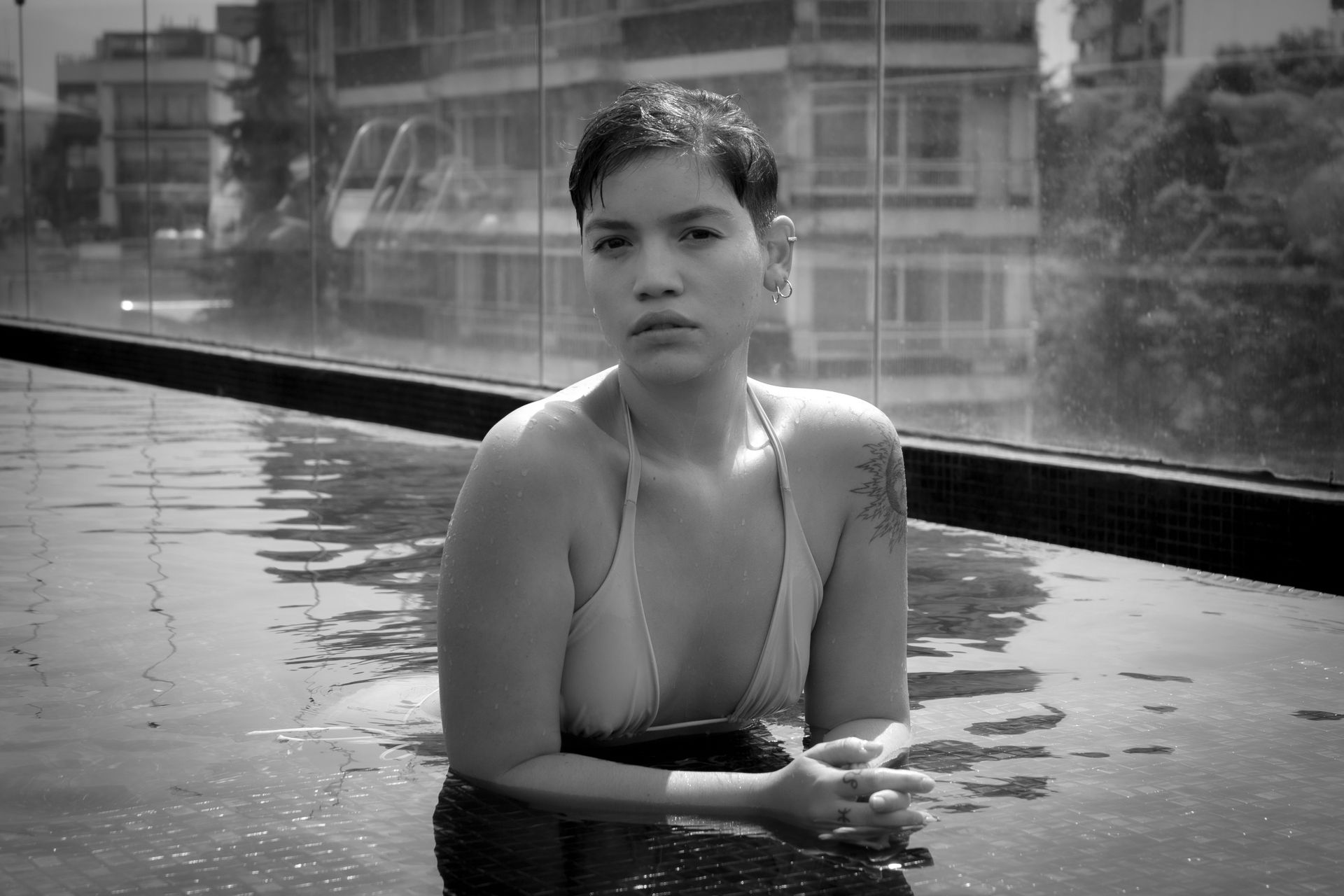 Elegant black and white portrait of a woman in an urban rooftop pool setting.