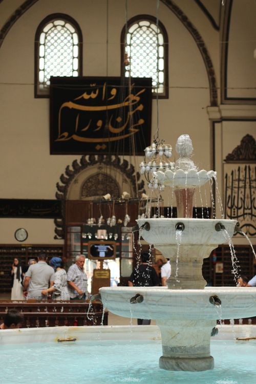 Free Beautiful interior of a historic mosque featuring an ornate fountain and Arabic calligraphy. Stock Photo