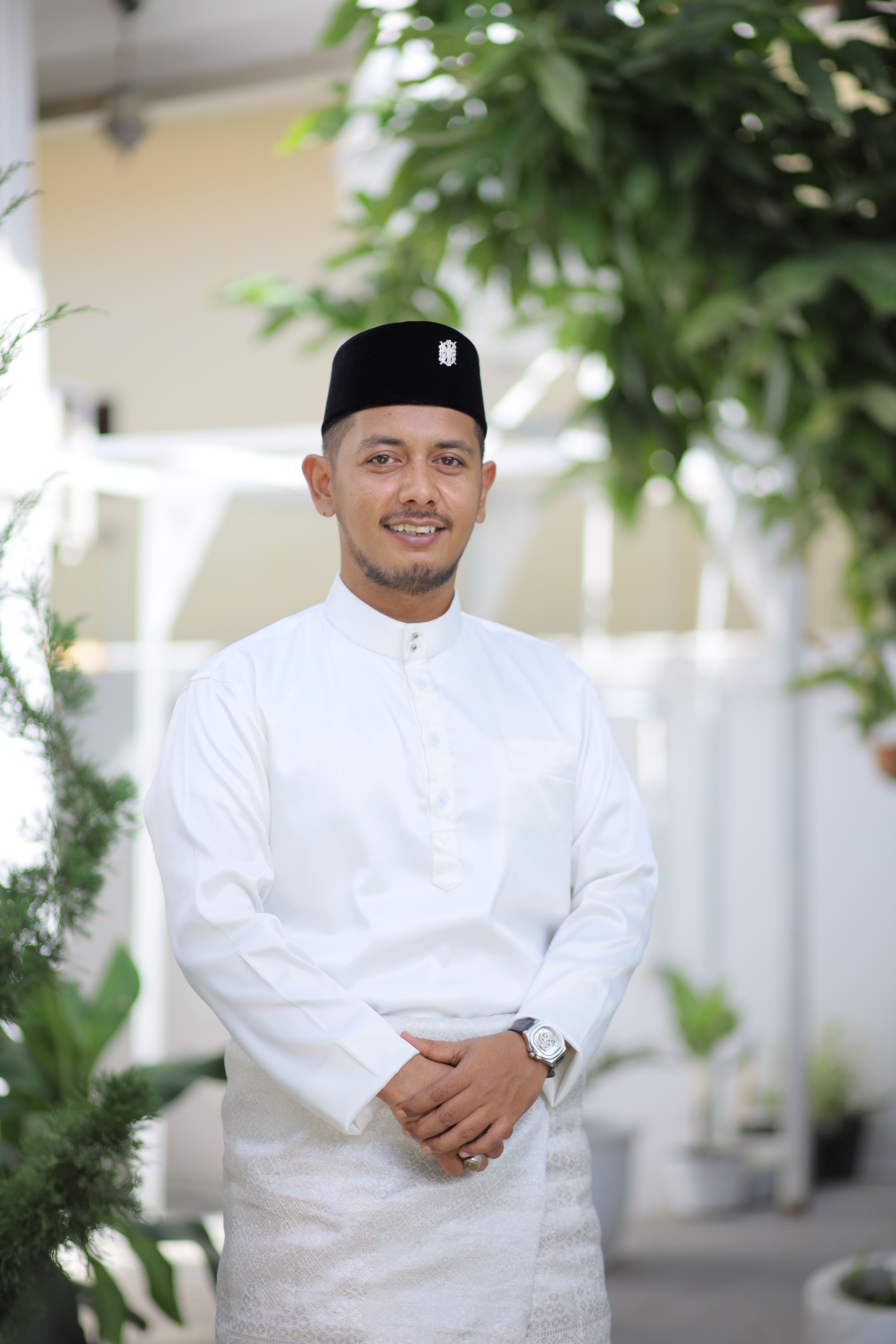 Portrait of a man in traditional Acehnese attire outdoors, embodying cultural elegance.