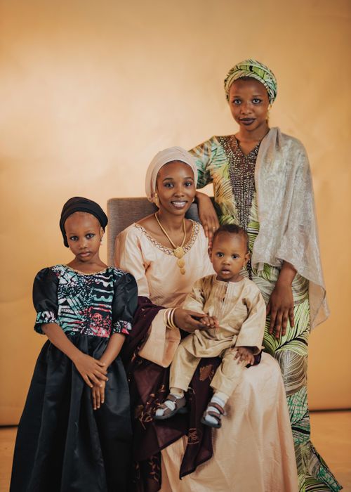 Free A family portrait featuring four people in traditional African attire against a warm backdrop. Stock Photo