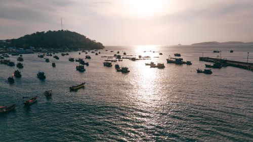 Free A serene view of fishing boats floating in Halong Bay, Vietnam at sunset. Stock Photo