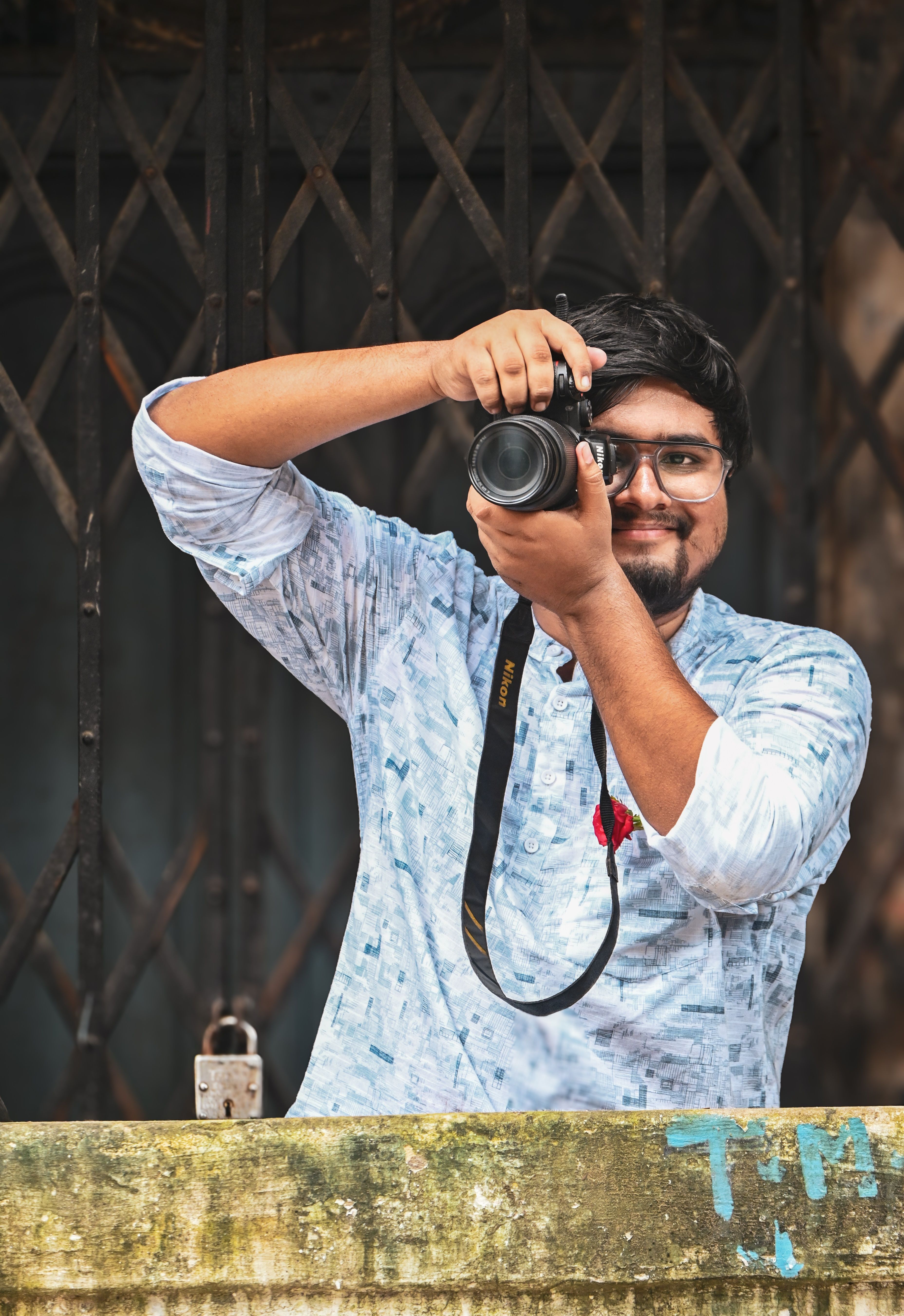 Smiling photographer in Kolkata, India, holding a DSLR camera ready to capture the moment.