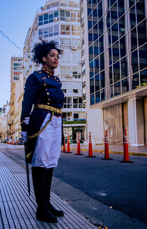 Free Woman in historical military attire stands confidently in modern Buenos Aires street. Stock Photo