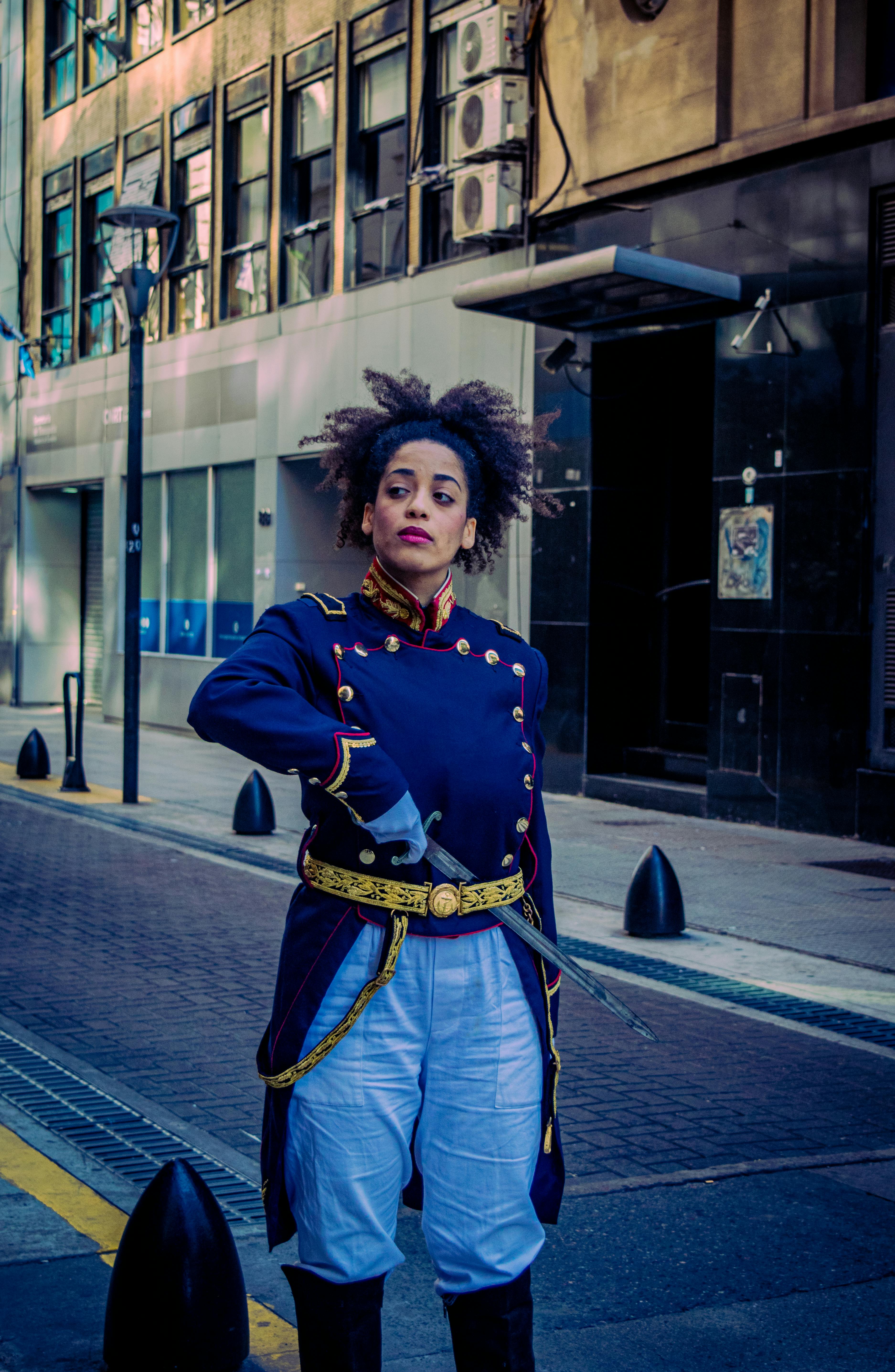 Woman in historical military costume poses confidently on Buenos Aires street.