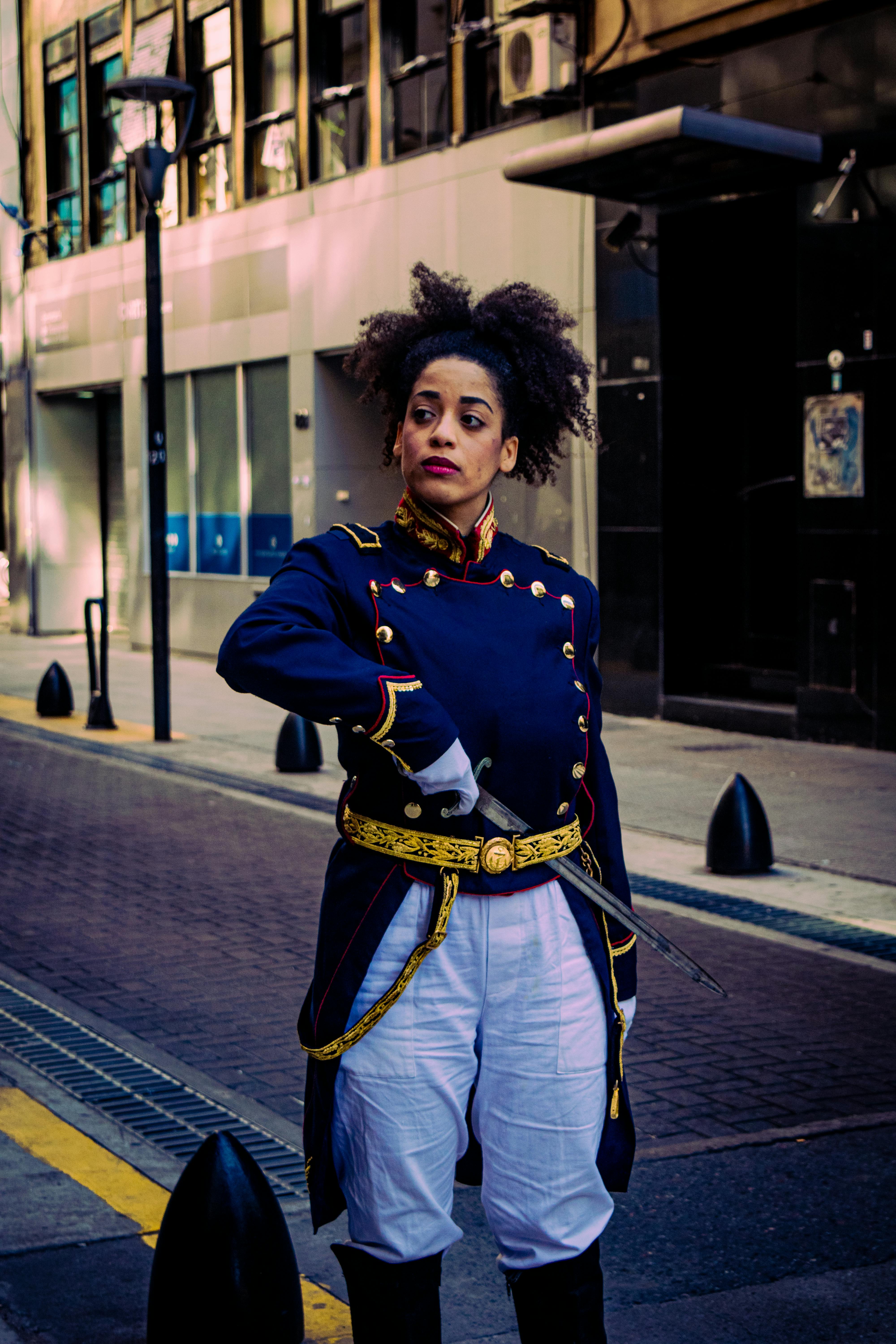 A woman in historical military attire stands confidently on a city street in Buenos Aires, Argentina.
