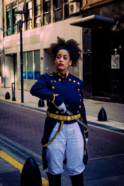 Free A woman in historical military attire stands confidently on a city street in Buenos Aires, Argentina. Stock Photo
