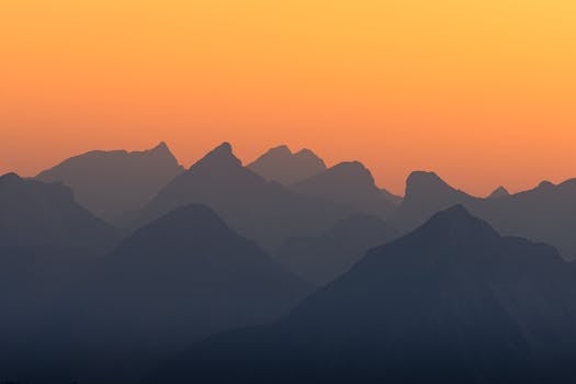 Serene mountain range silhouettes against a vibrant sunset sky.