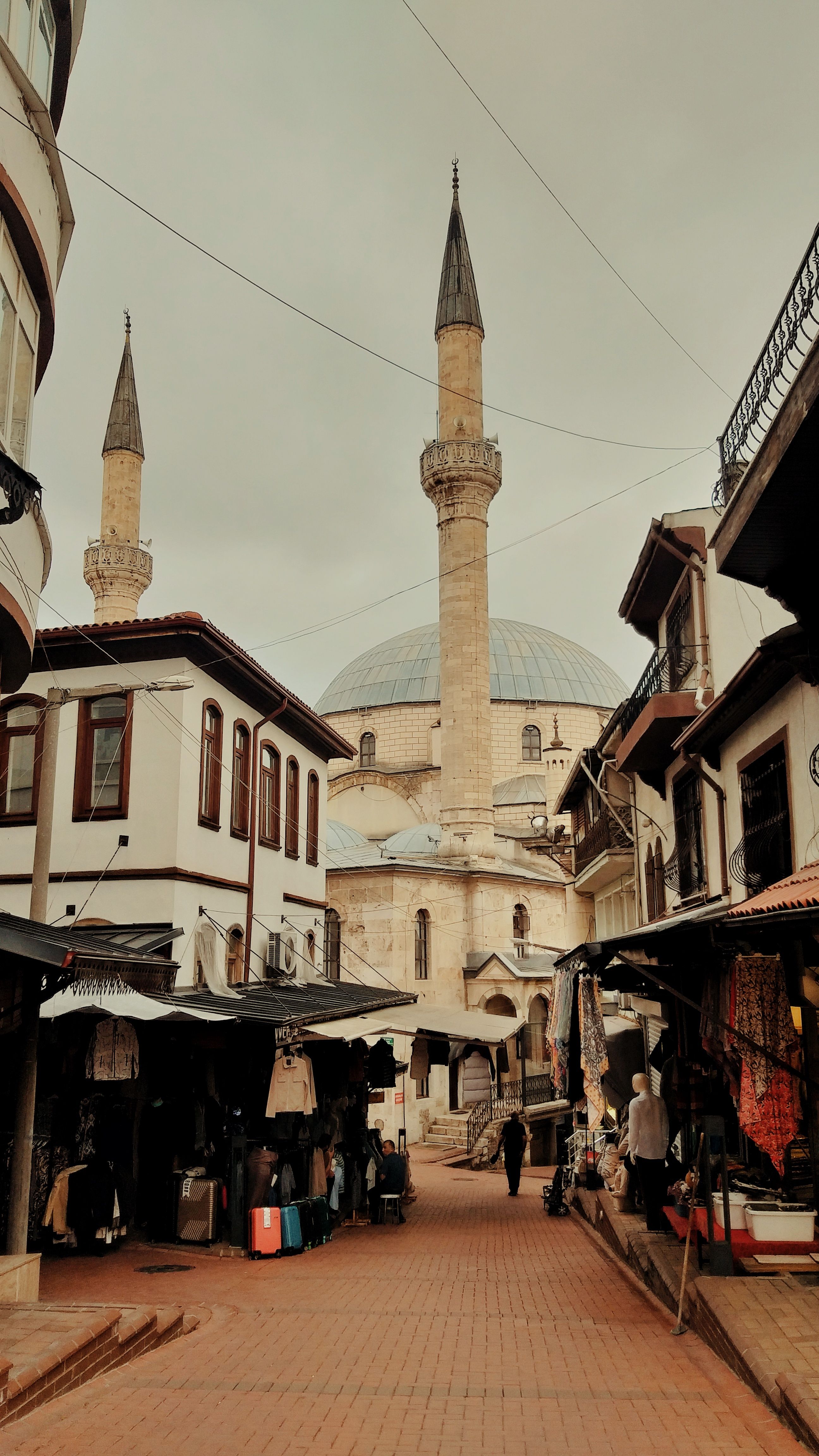 A bustling market street leading to a historic mosque in Bolu, Türkiye, capturing the essence of traditional architecture.
