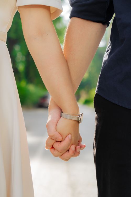 Free Close-up of a couple holding hands outdoors, symbolizing love and connection on a sunny day. Stock Photo
