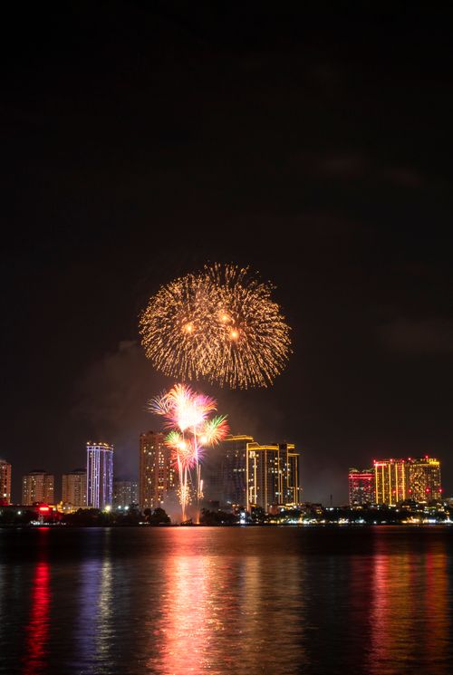 Free Colorful fireworks illuminating the night sky above an urban skyline, reflecting across the water. Stock Photo