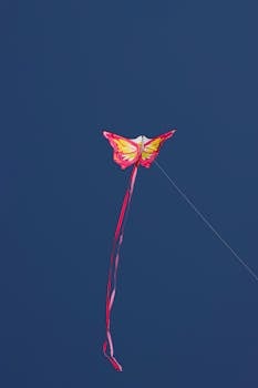 Vibrant butterfly-shaped kite soaring high in a deep blue sky in Corfu, Greece.