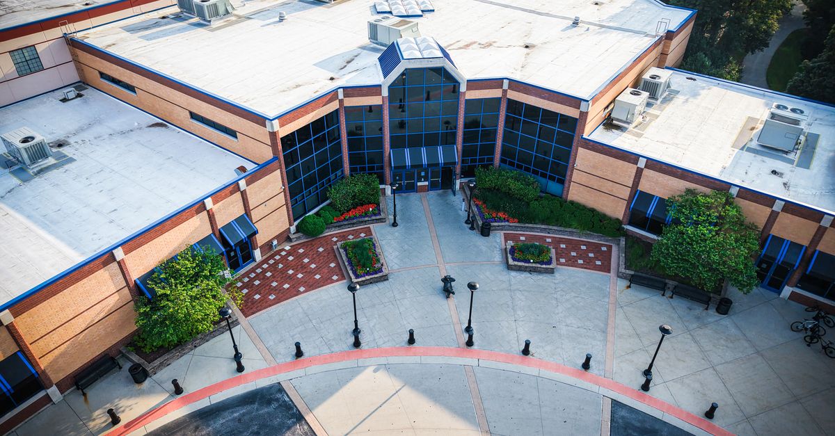 Aerial view of a modern building with glass windows and landscaped entrance.
