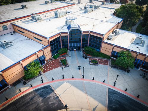 Free Aerial view of a modern building with glass windows and landscaped entrance. Stock Photo