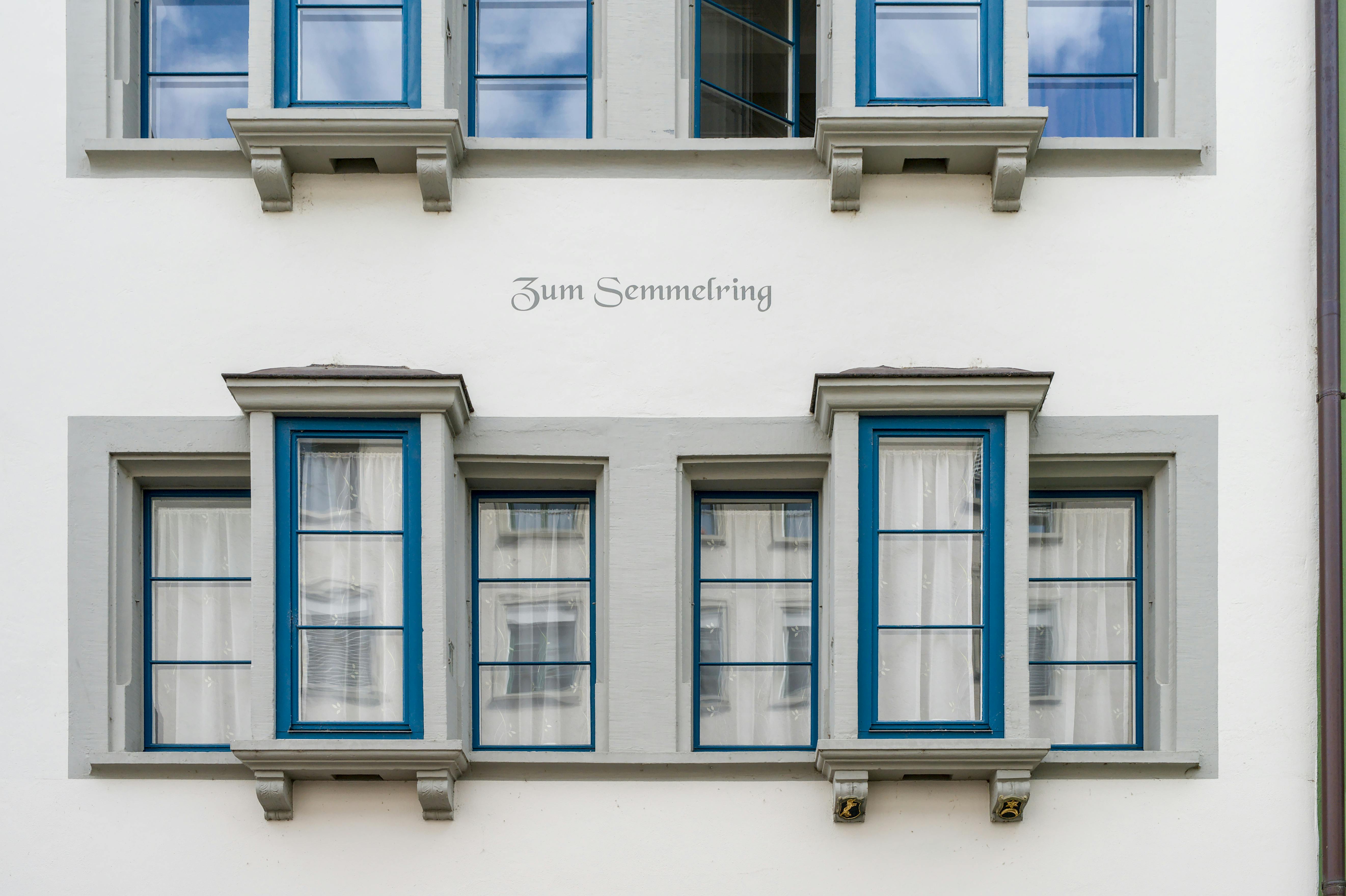 Detail of traditional Swiss architecture with distinctive blue-framed windows and decorative text.