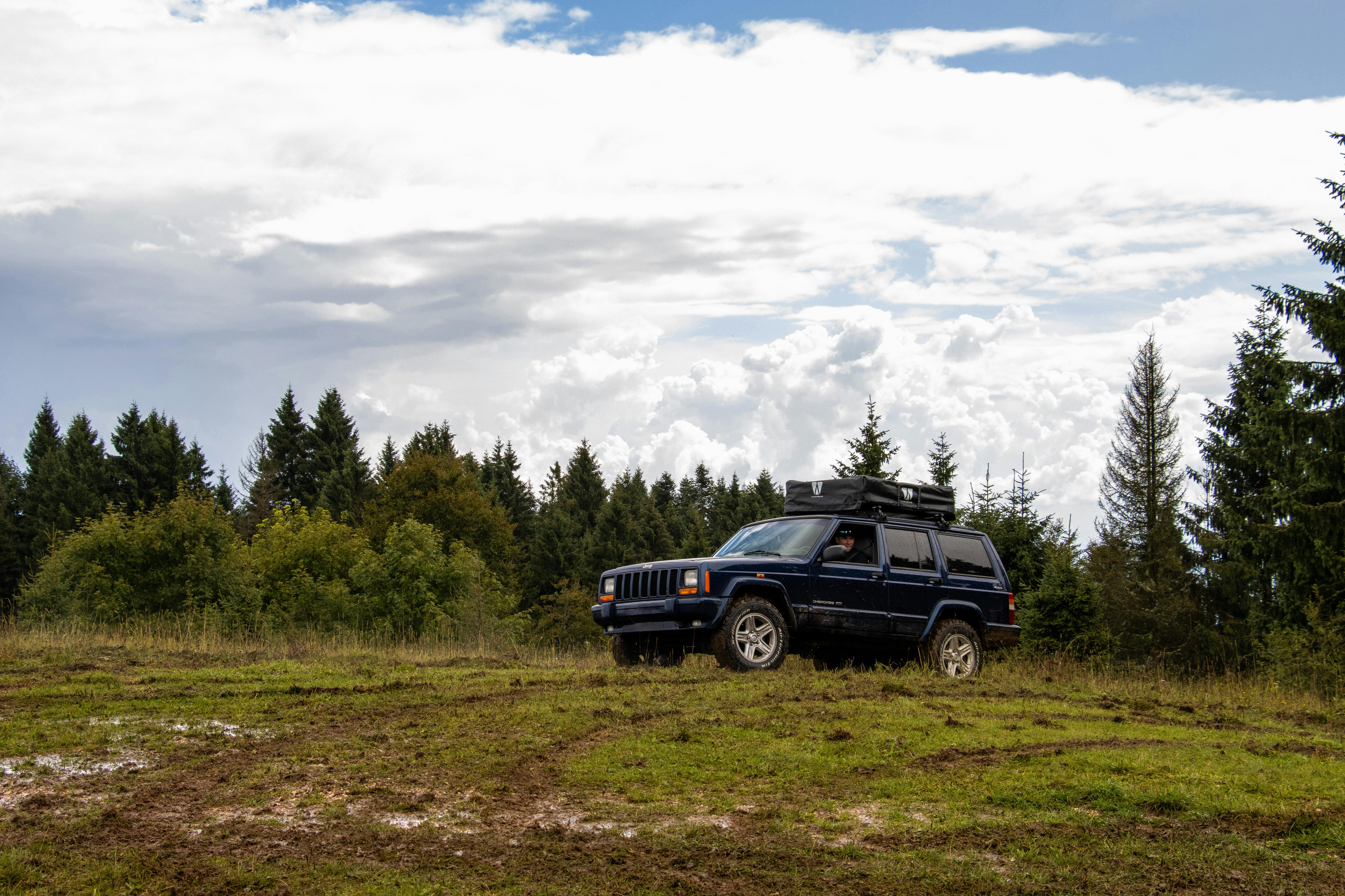 Explore off-road adventure in Asiago, Veneto with a rugged 4x4 Jeep amidst forested mountains.