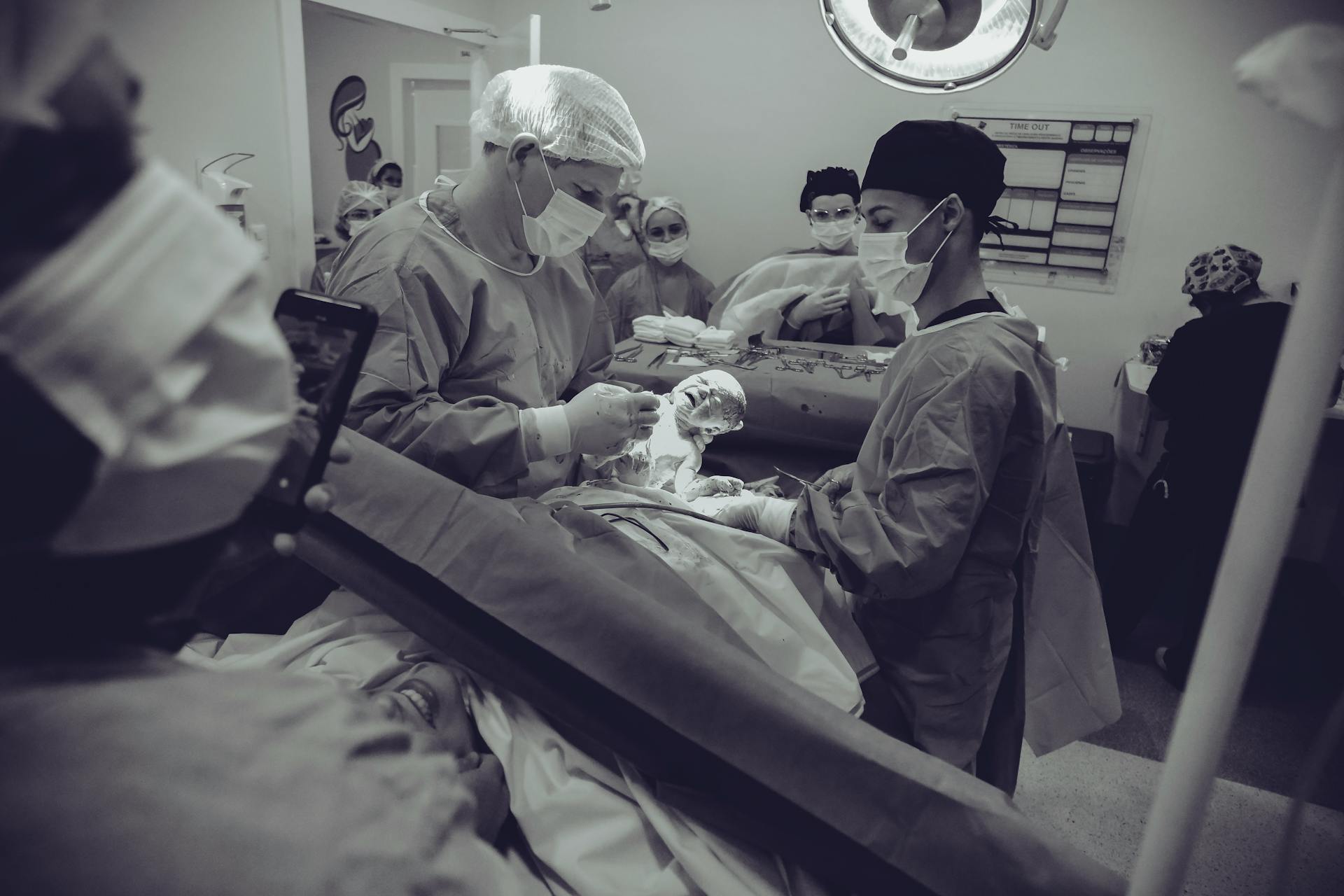 Medical team delivering a newborn via cesarean section in a hospital operating room.