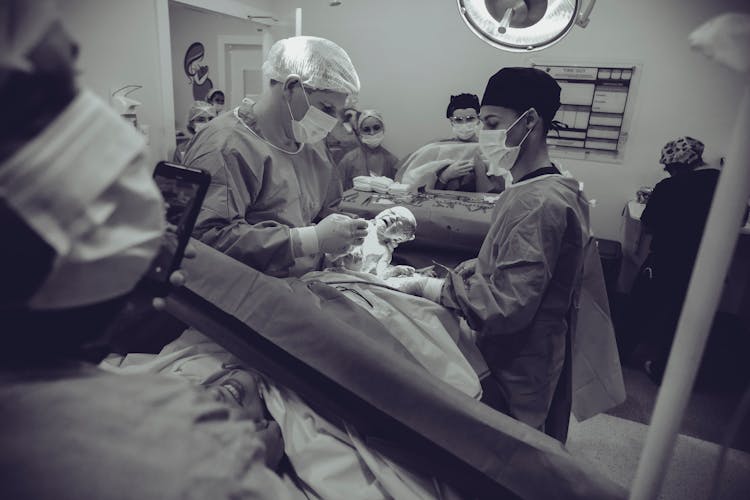Grayscale Photography Of Doctor Holding Baby