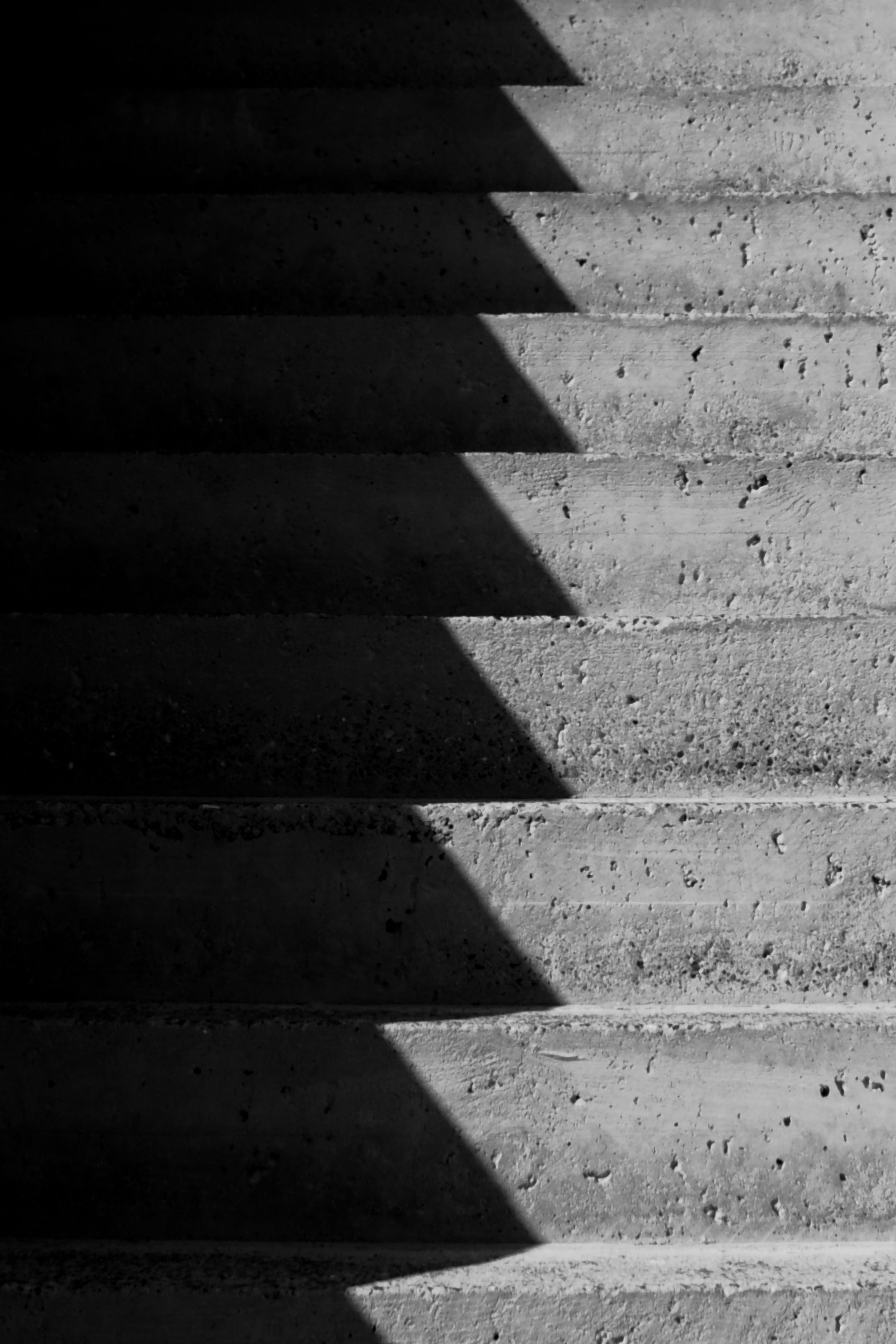 Abstract monochrome image of concrete stairs with dramatic shadows.