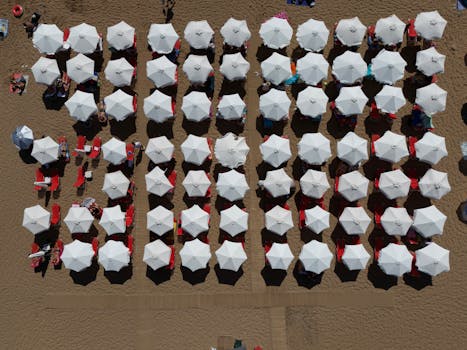 A stunning overhead shot of beach umbrellas aligned on a sandy beach in Corfu, Greece.
