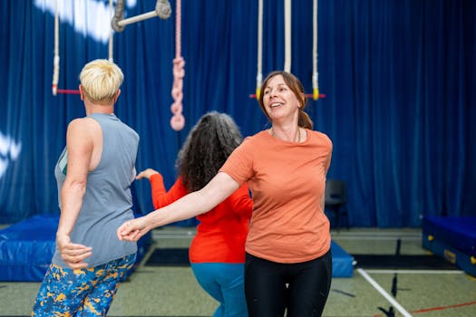 Group of adults engaging in a trapeze rehearsal indoors, smiling and having fun.