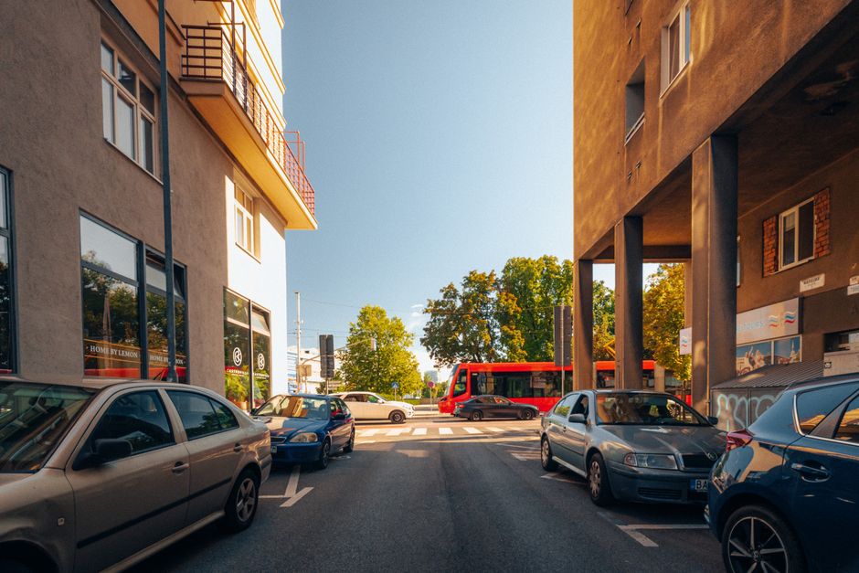 A red public bus in Bratislava, Slovakia, driving past historic buildings.