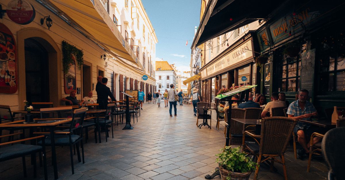 traveler sitting at a sidewalk cafe in a European old town watching locals walk by