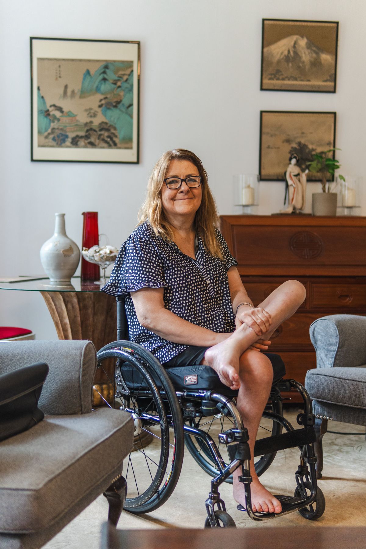 A smiling woman seated comfortably in a cosy, light-filled living room