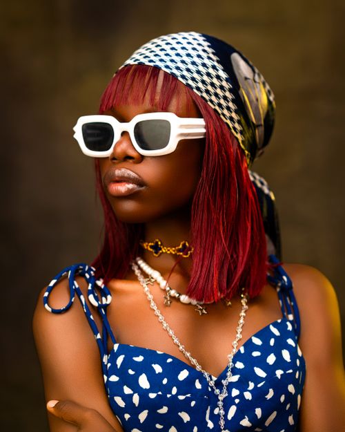 Free Portrait of a fashionable woman in white sunglasses, headscarf, and layered necklaces. Stock Photo